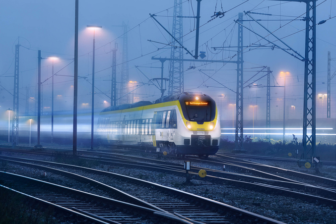 Le train jaune et blanc de la SWEG circule de nuit.
