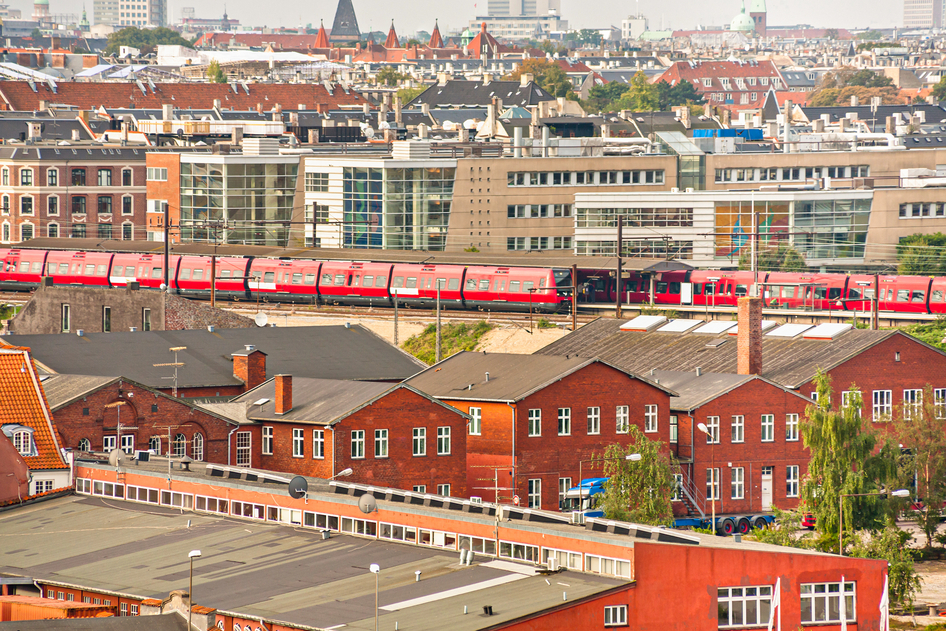 Vue aérienne de deux trains rouges de la DSB à une gare entre des maisons à Copenhague.