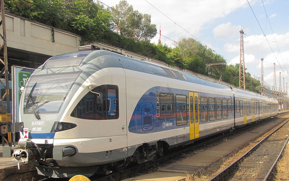Moderner Stadler FLIRT Triebzug in den Farben von MÁV-START (blau-weiß) in einem alten Regionalbahnhof