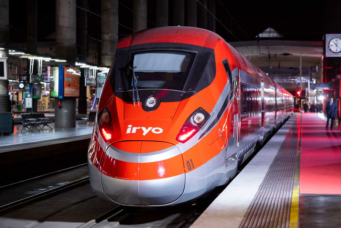 Une photo de face d'un train iryo rouge et sylvestre stationné sur la voie de la gare.