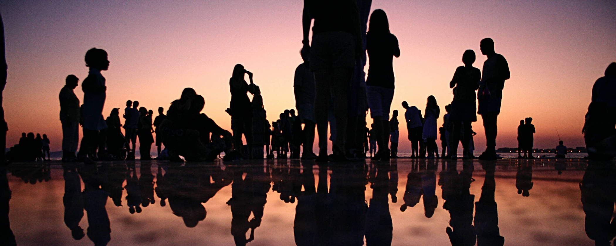 Silhouette noire de personnes sur l'eau au coucher du soleil