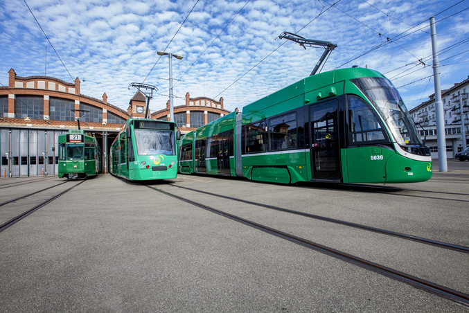 Drei grüne Trams der Basler Verkehrsbetriebe fahren aus einem Bahnhof auf die Kamera zu