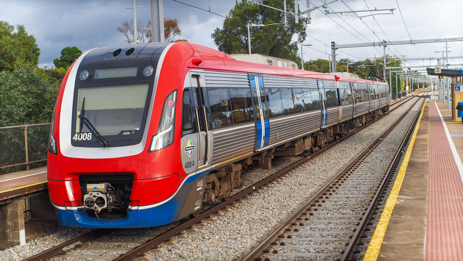 Ein rot-blau-silberner Keolis Zug fährt in einen kleinen Bahnhof ein.
