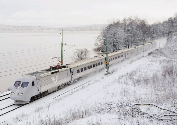Train SJ blanc dans la neige devant un lac gelé.
