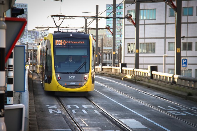 Un tramway jaune et noir de la province d'Utrecht se trouve à une station.