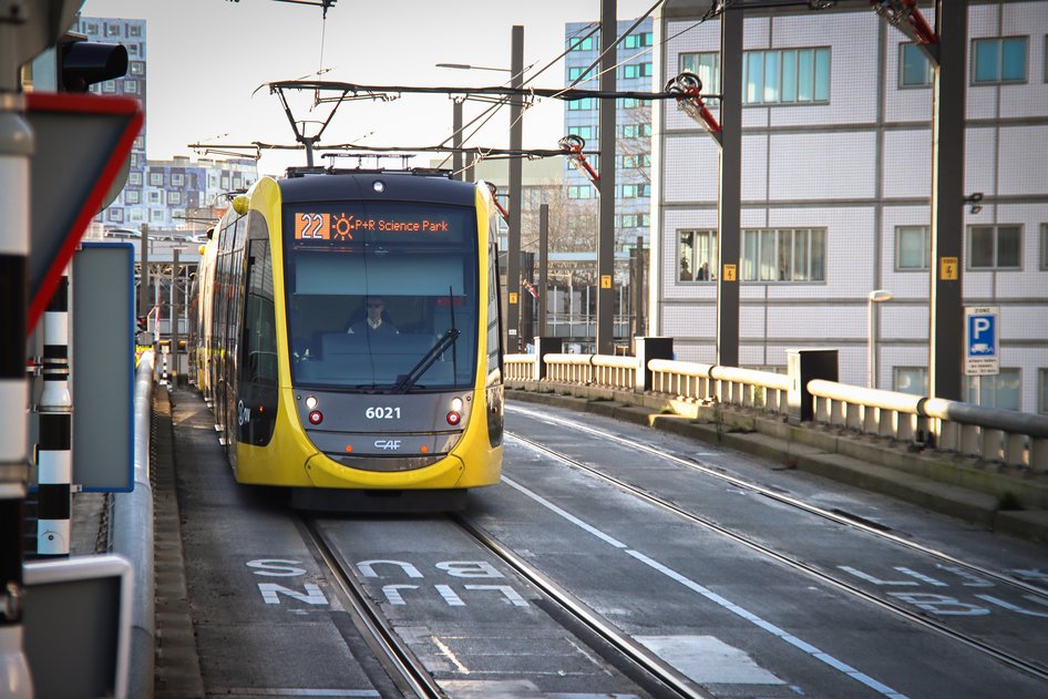 Un tramway jaune et noir de la province d'Utrecht se trouve à une station.