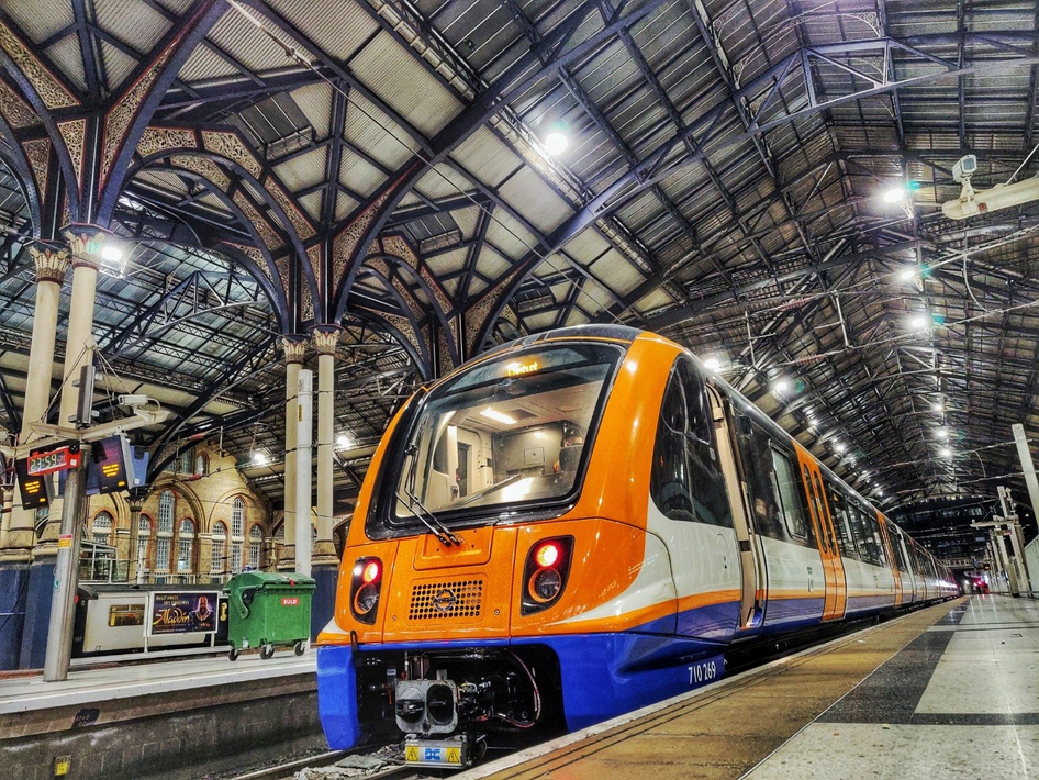 Un train orange d'Arriva Rail London se trouve dans une gare londonienne.