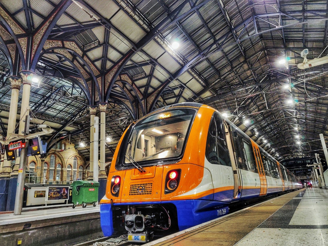 Un train orange d'Arriva Rail London se trouve dans une gare londonienne.