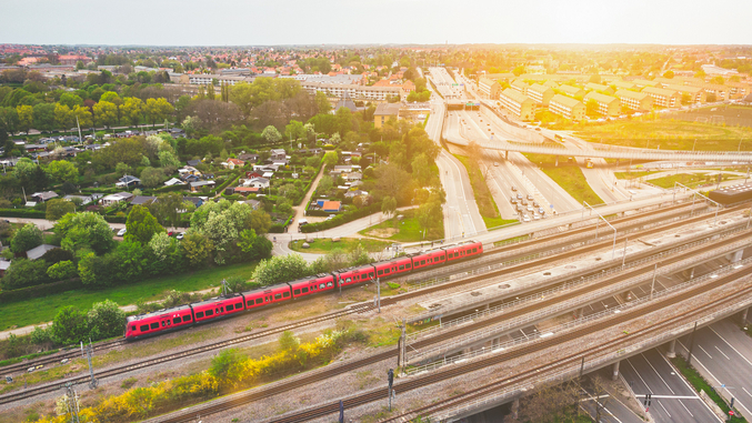 Vue aérienne d'un train de banlieue rouge de DSB traversant Copenhague devant le soleil couchant.