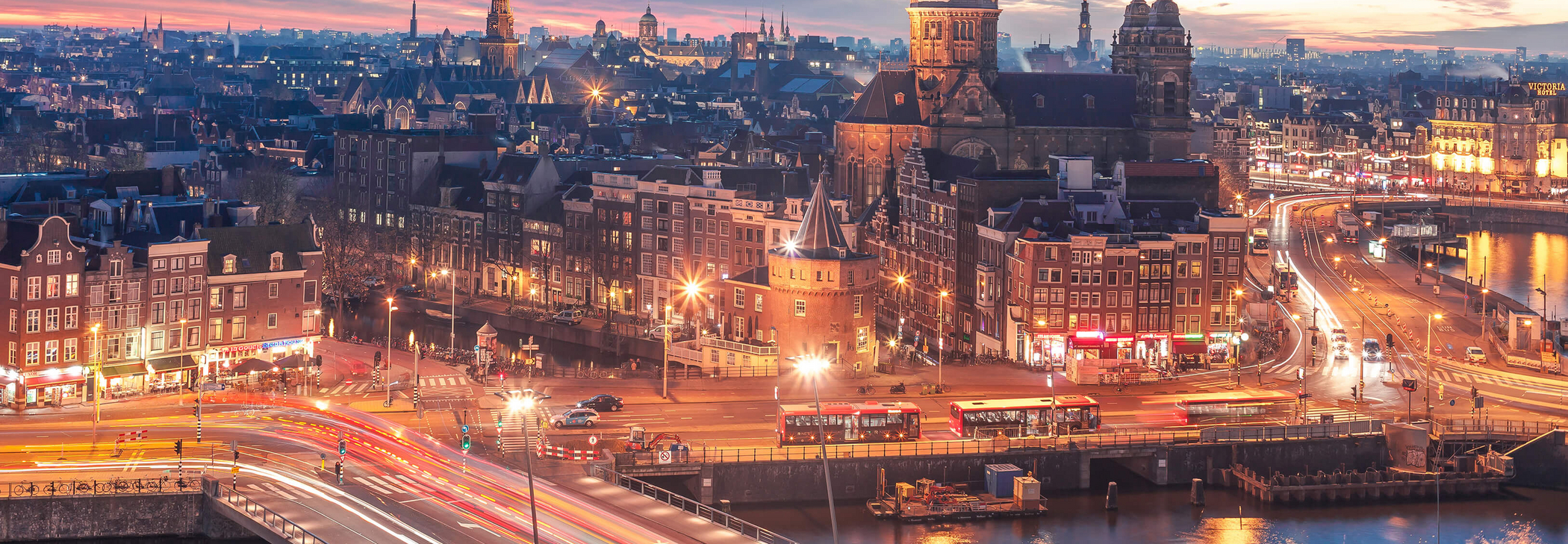 Skyline von Amsterdam in der Dämmerung mit hellen Lichtern
