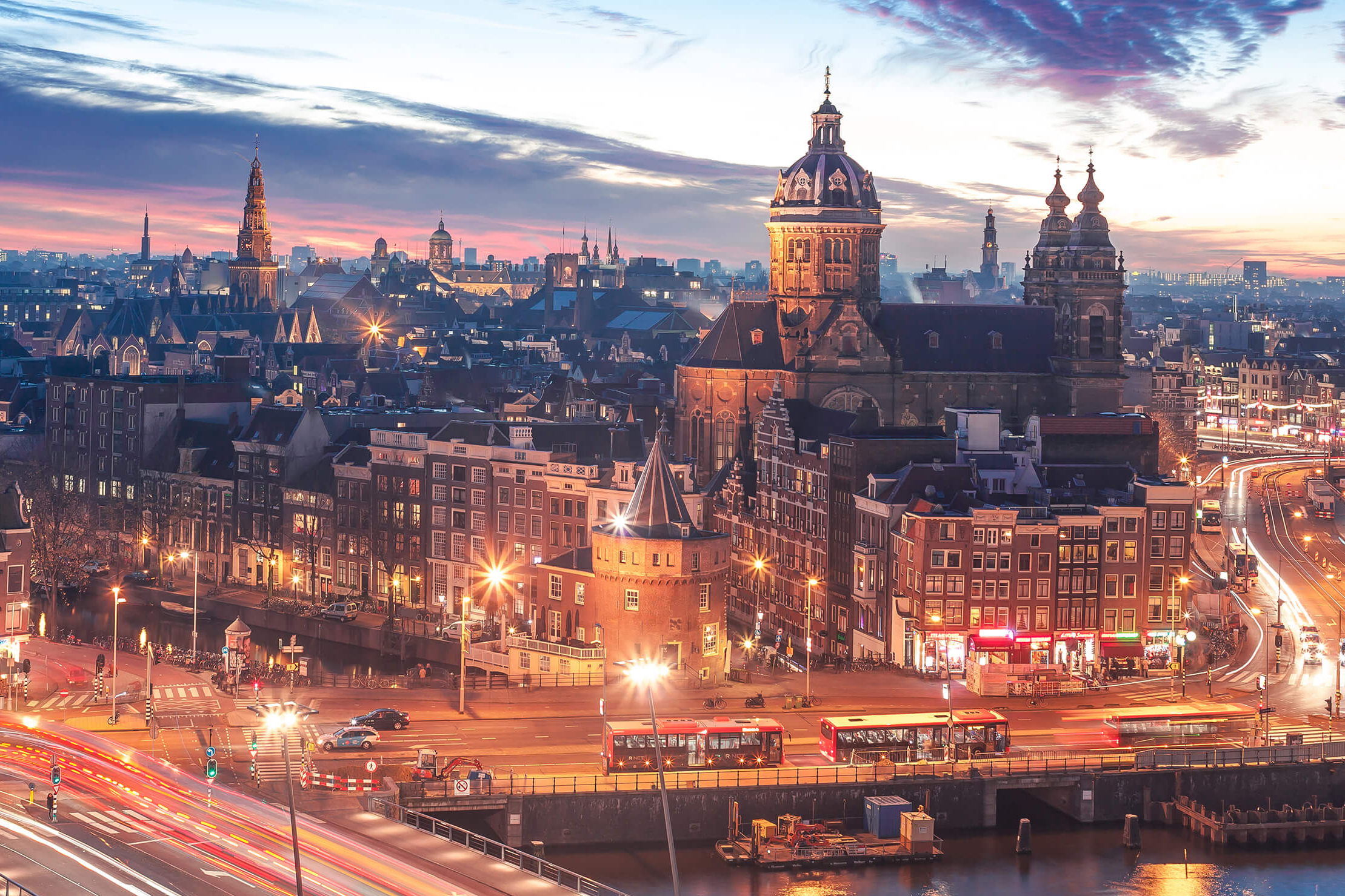 Skyline von Amsterdam in der Dämmerung mit hellen Lichtern