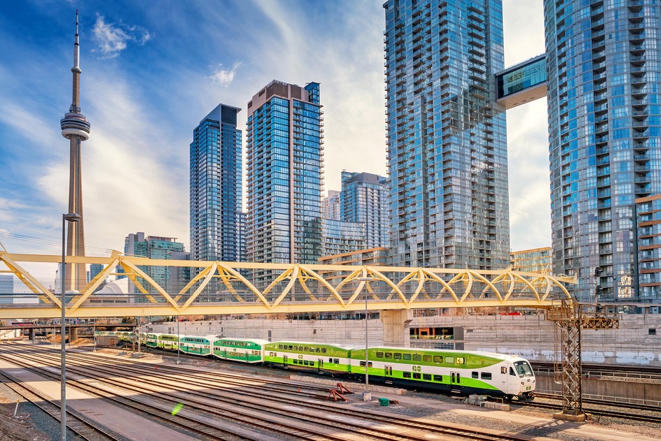 Un train régional blanc et vert de GO Transit devant des gratte-ciel à Toronto