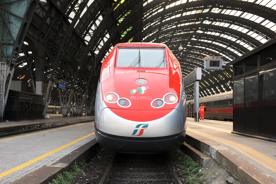 Roter Trenitalia Zug fährt in einen Bahnhof
