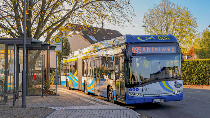 Un bus bleu de la SWS se trouve à un arrêt de bus à Solingen au coucher du soleil.